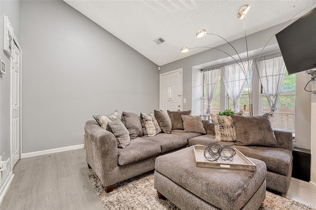 living room with lofted ceiling, light wood-type flooring, visible vents, and baseboards