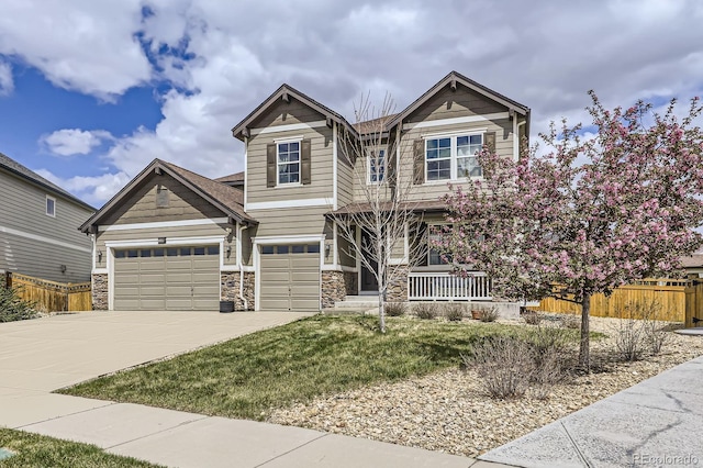 craftsman inspired home with covered porch, fence, a front lawn, concrete driveway, and stone siding