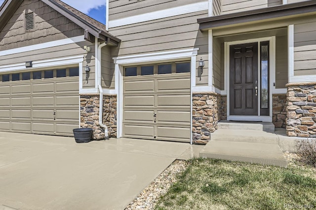 property entrance with an attached garage, driveway, and stone siding