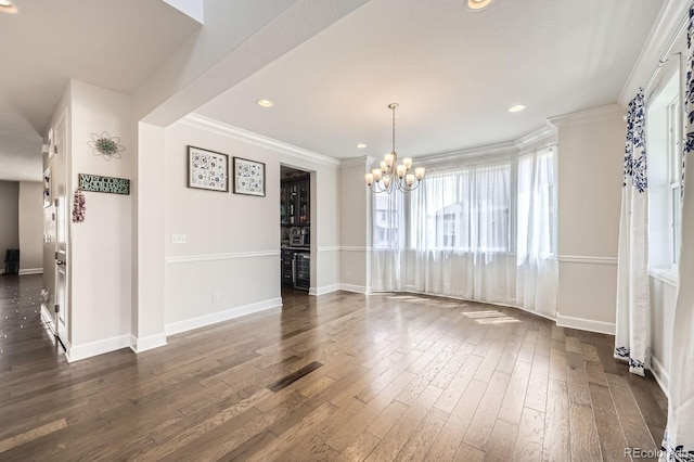 unfurnished dining area featuring an inviting chandelier, baseboards, crown molding, and dark wood-style floors