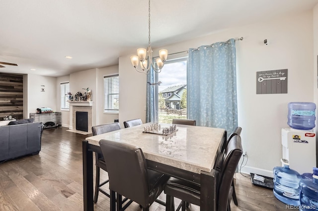 dining room featuring an inviting chandelier, recessed lighting, baseboards, a fireplace with flush hearth, and wood finished floors