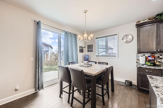dining area featuring plenty of natural light, dark wood-type flooring, and a notable chandelier