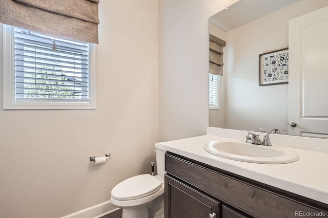 bathroom with toilet, baseboards, and vanity