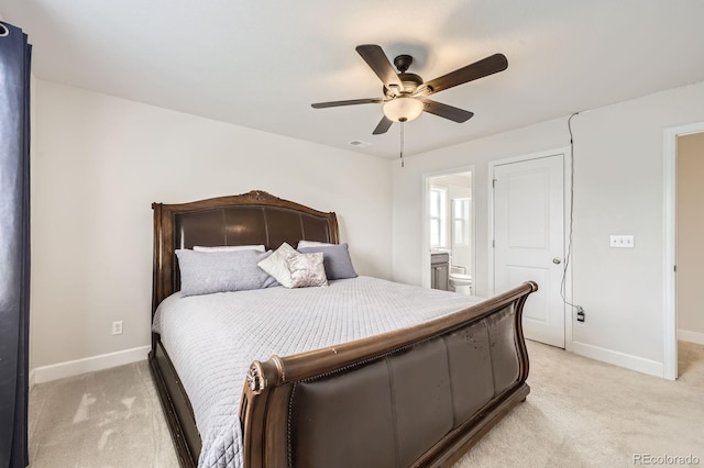 bedroom featuring baseboards, ceiling fan, ensuite bath, and light carpet