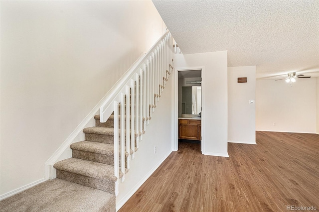 stairway featuring hardwood / wood-style flooring, a textured ceiling, and ceiling fan