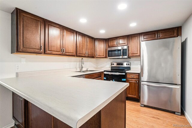 kitchen featuring light hardwood / wood-style floors, stainless steel appliances, kitchen peninsula, and sink