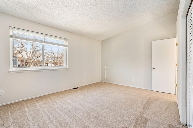 carpeted empty room with vaulted ceiling and a textured ceiling