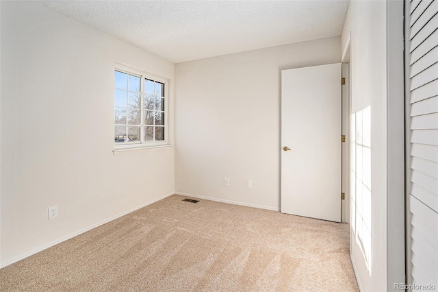 carpeted empty room featuring a textured ceiling