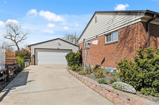 view of side of home featuring brick siding, an outdoor structure, a garage, and fence