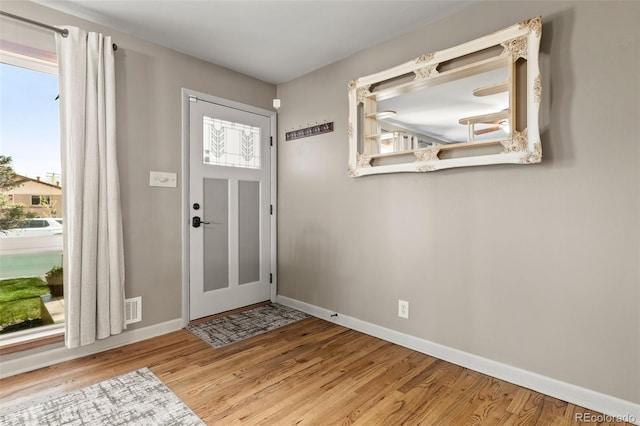 foyer with baseboards, plenty of natural light, and wood finished floors