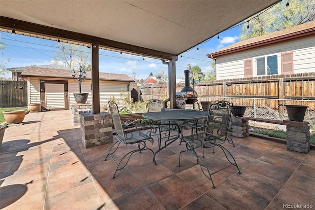 view of patio featuring a fenced backyard, an outbuilding, and outdoor dining space