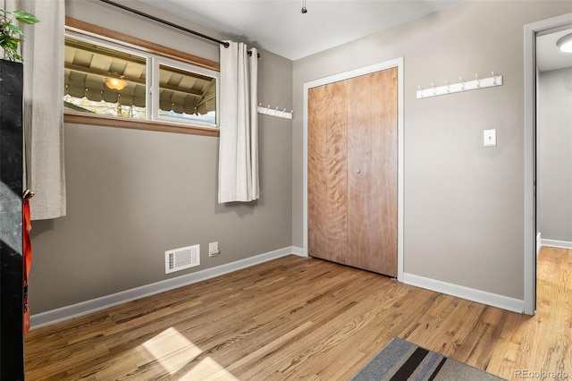 unfurnished bedroom featuring baseboards, a closet, wood finished floors, and visible vents