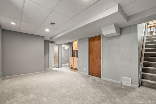 finished basement with visible vents, stairs, baseboards, and light carpet