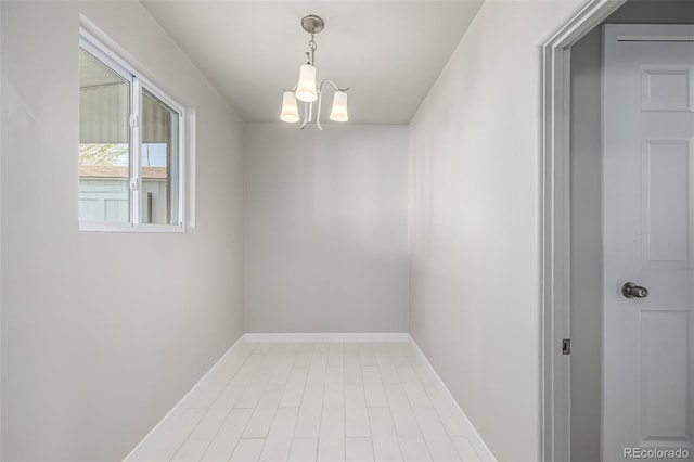 spare room with a notable chandelier and baseboards