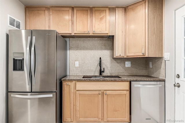 kitchen with appliances with stainless steel finishes, visible vents, decorative backsplash, a sink, and light brown cabinetry