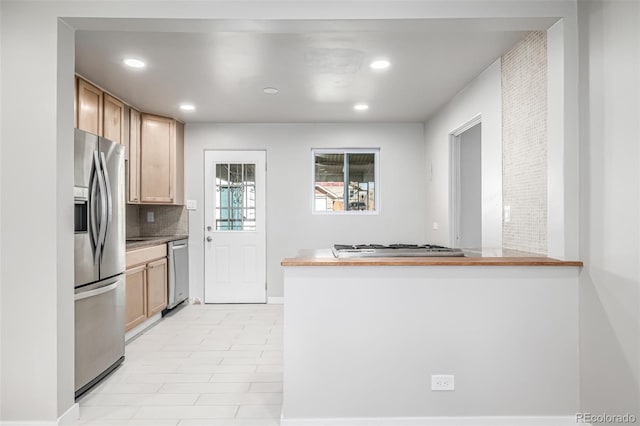 kitchen with tasteful backsplash, a peninsula, recessed lighting, appliances with stainless steel finishes, and baseboards
