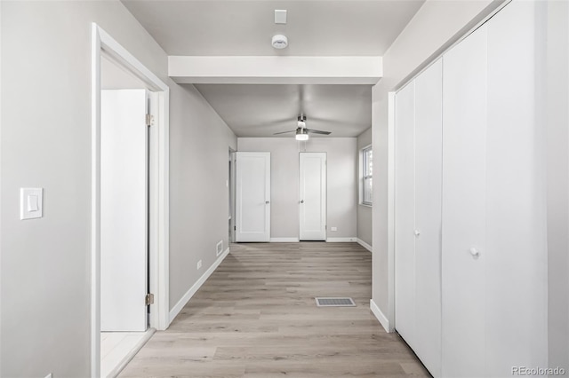 hallway with visible vents, baseboards, and light wood finished floors
