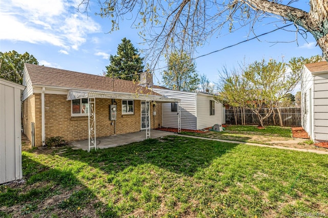 back of property with a fenced backyard, a lawn, a patio area, brick siding, and a chimney