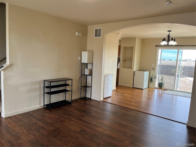 unfurnished room with dark hardwood / wood-style floors and an inviting chandelier