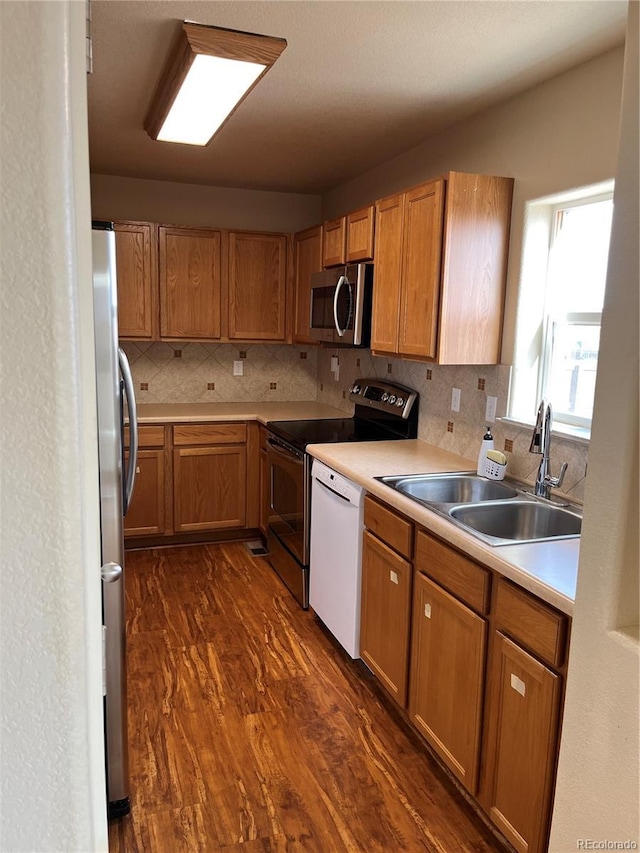 kitchen with stainless steel appliances, dark hardwood / wood-style flooring, tasteful backsplash, and sink