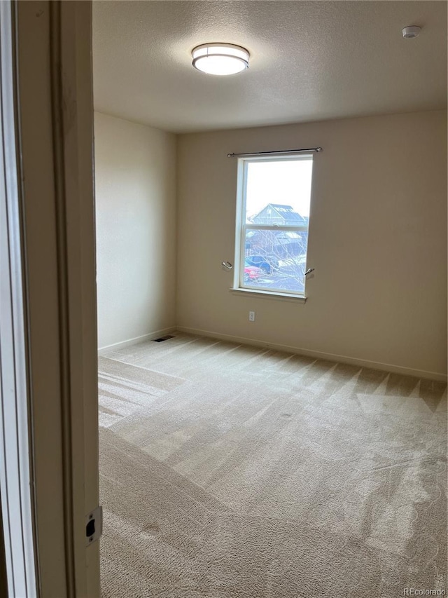 empty room with light carpet and a textured ceiling