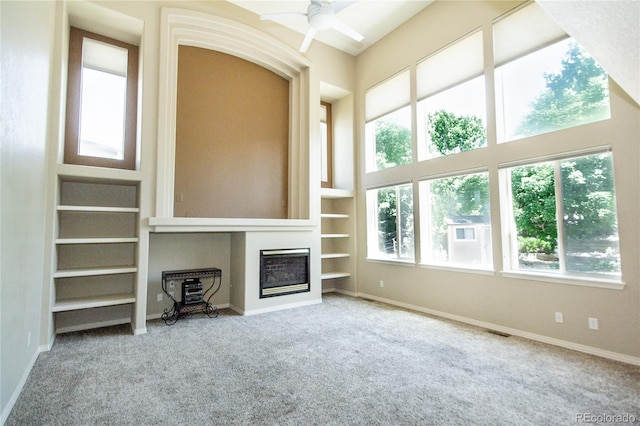 17672 E Weaver Pl, Aurora, CO 80016 - unfurnished living room with carpet flooring, built in shelves, ceiling fan, and a glass covered fireplace