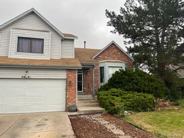 20391 E 42nd Ave, Denver, CO 80249 - view of front of home featuring brick siding, driveway, a garage, and roof with shingles