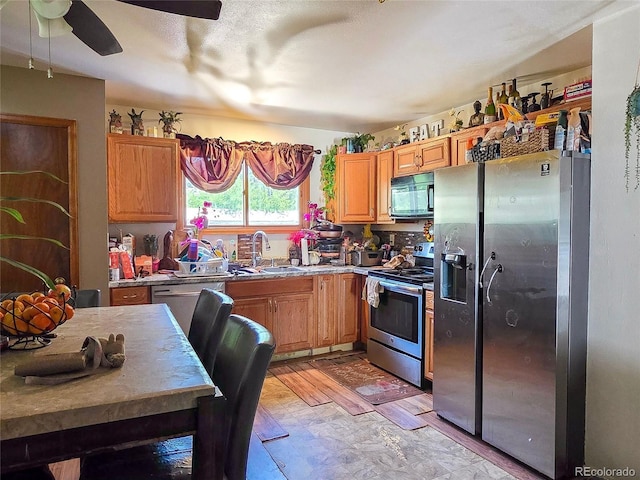 20391 E 42nd Ave, Denver, CO 80249 - kitchen with stainless steel appliances, a ceiling fan, and brown cabinetry