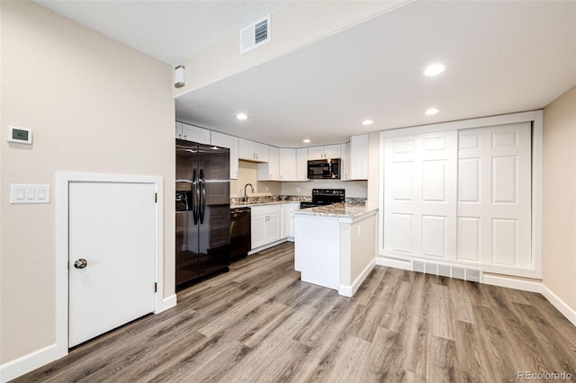 kitchen with black appliances, light wood-type flooring, white cabinetry, a peninsula, and recessed lighting