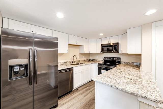 kitchen featuring stainless steel appliances, a sink, light wood finished floors, white cabinets, and light stone counters