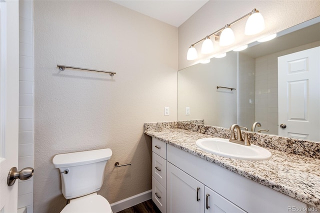 bathroom featuring toilet, vanity, and wood finished floors
