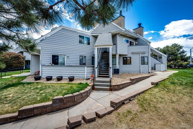 view of front of home with a chimney, a front yard, and stairs