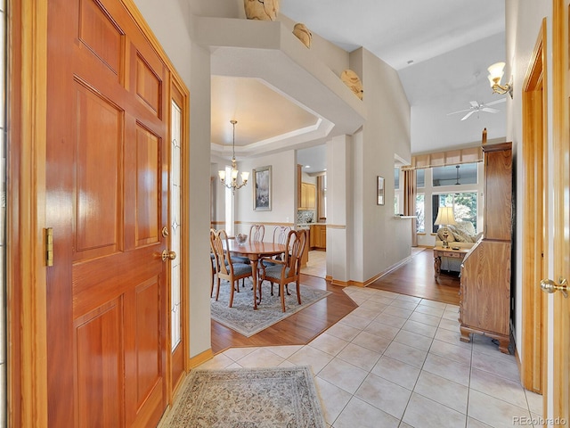 entryway with vaulted ceiling, ceiling fan with notable chandelier, and light wood-type flooring