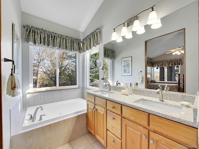 bathroom with tile patterned floors, vanity, vaulted ceiling, ceiling fan, and tiled tub