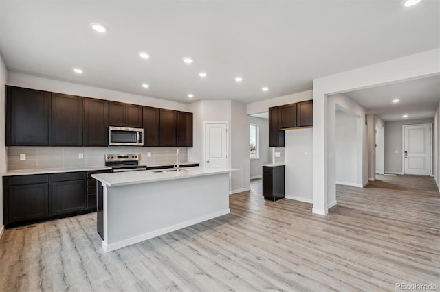 kitchen featuring stainless steel appliances, light hardwood / wood-style flooring, and an island with sink