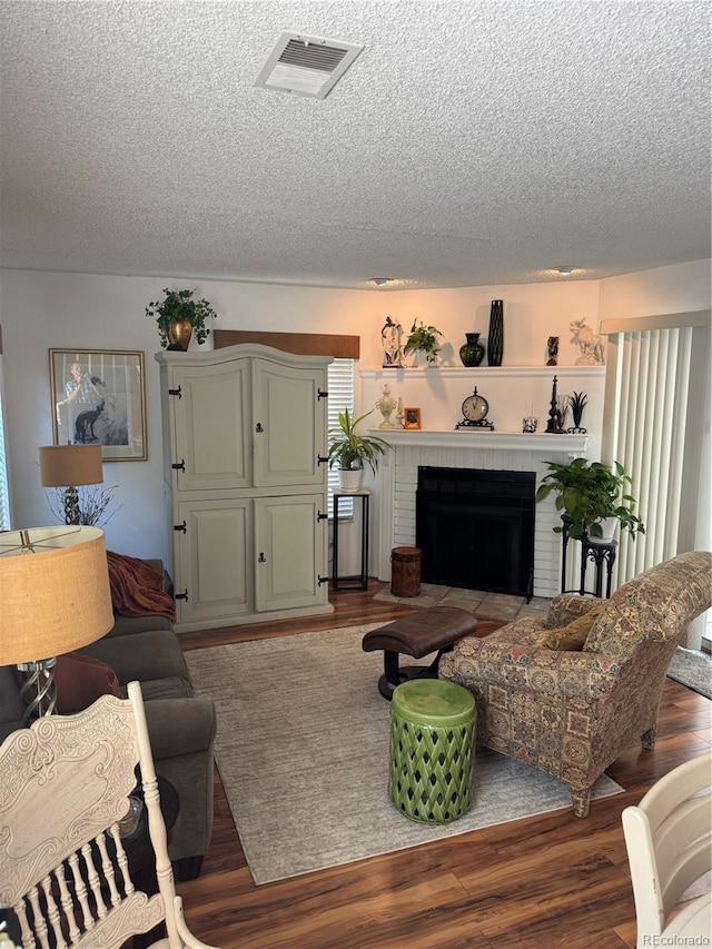12534 E Pacific Cir Unit A, Aurora, CO 80014 - living room featuring a textured ceiling, a brick fireplace, and wood finished floors