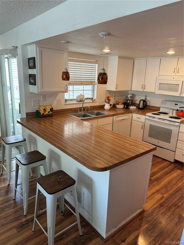 12534 E Pacific Cir Unit A, Aurora, CO 80014 - kitchen with white appliances, wood counters, a peninsula, a breakfast bar area, and a textured ceiling