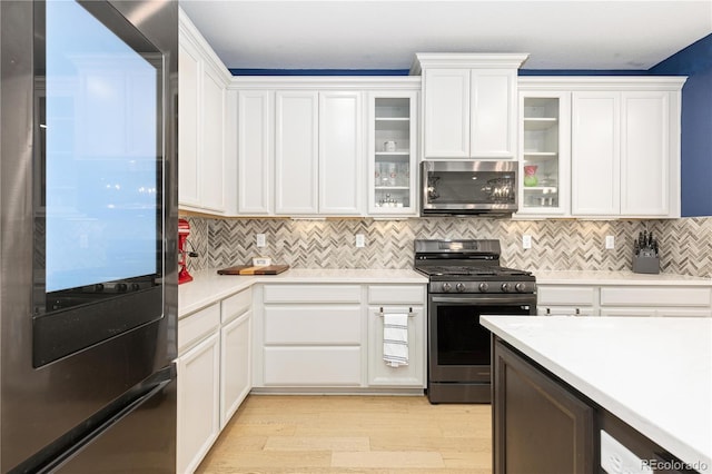 kitchen featuring tasteful backsplash, light wood-type flooring, white cabinets, and appliances with stainless steel finishes