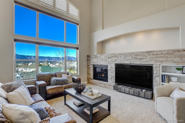 living room with a fireplace, a high ceiling, and a mountain view