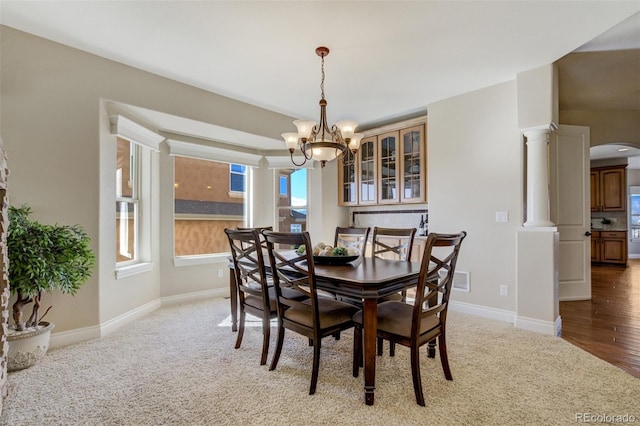 dining room with ornate columns, baseboards, arched walkways, and an inviting chandelier