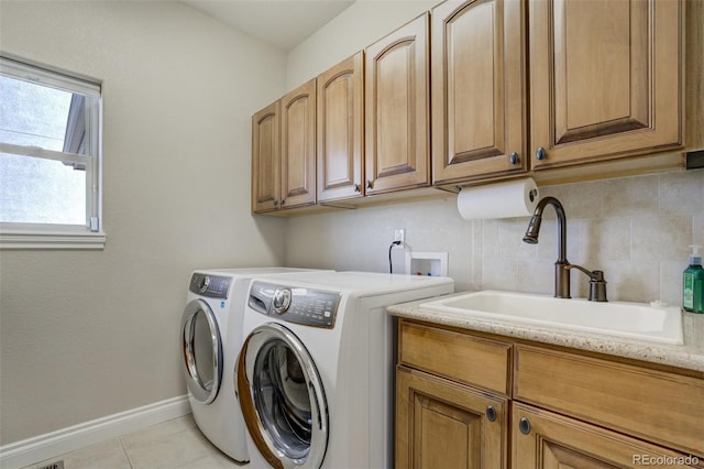 clothes washing area featuring light tile patterned floors, a sink, baseboards, cabinet space, and washing machine and clothes dryer