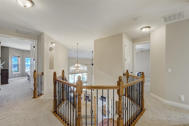 corridor with carpet, visible vents, an inviting chandelier, an upstairs landing, and baseboards