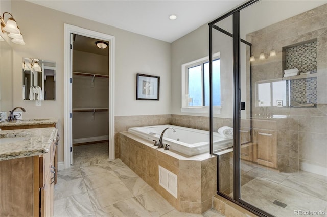 bathroom with visible vents, vanity, a spacious closet, a shower stall, and a bath