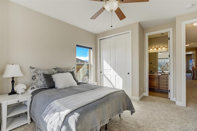 bedroom with ceiling fan, light colored carpet, baseboards, a closet, and ensuite bath