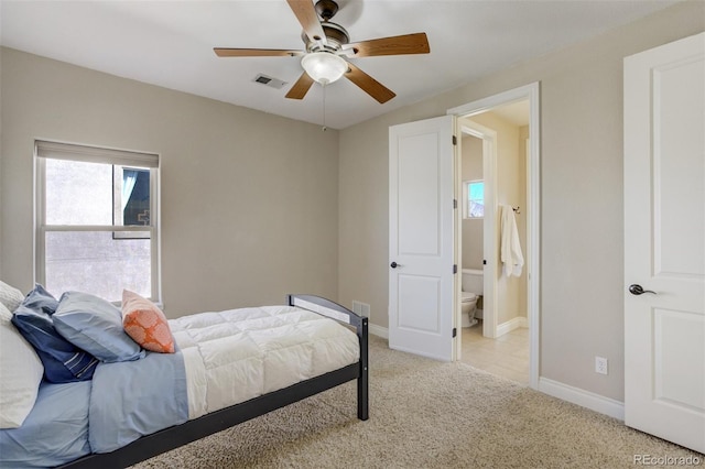 bedroom featuring light colored carpet, visible vents, ensuite bathroom, a ceiling fan, and baseboards