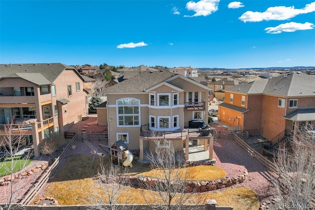 rear view of property featuring a residential view, driveway, a balcony, and stucco siding