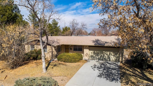 ranch-style house with brick siding, an attached garage, concrete driveway, and roof with shingles