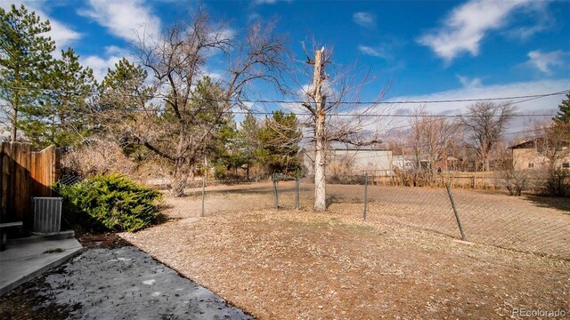 view of yard featuring central AC and fence