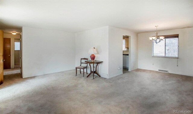 unfurnished room featuring light carpet, visible vents, and a notable chandelier