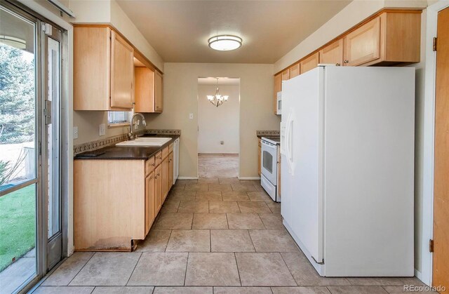 kitchen featuring a sink, white appliances, dark countertops, and light brown cabinetry